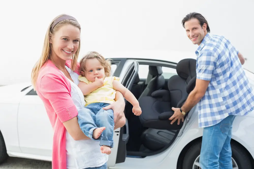 Parents carrying baby and her car seat out of the car